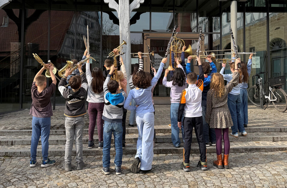 Eine Bläserklasse hält posend ihre Instrumente in die Luft