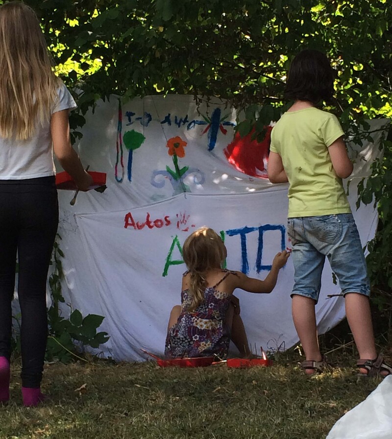 Mehrere Kinder bemalen eine weiße Leinwand